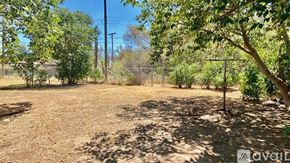 Lubbock house for rent - A backyard with a dirt ground and trees.