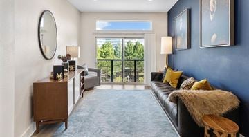 Lehi apartment for rent - A living room with a black couch and a round mirror on the wall.