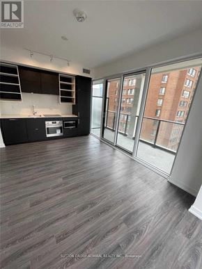 Toronto (Bay Street Corridor) condo for rent - A spacious room with wood flooring and a kitchen area with a stove and cabinets.