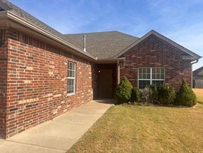 Centerton house for rent - A brick house with a brown roof and a small front yard.