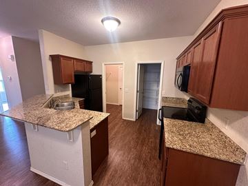 Centerton house for rent - A kitchen with brown cabinets and a granite countertop.