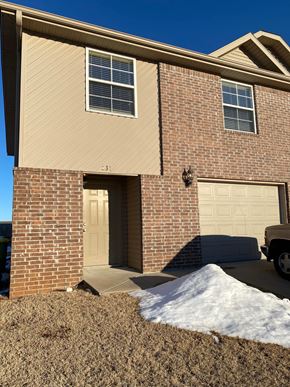 Centerton house for rent - A house with a brown brick facade and a tan garage door.