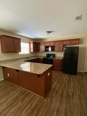 Centerton house for rent - A kitchen with brown cabinets and a black refrigerator.