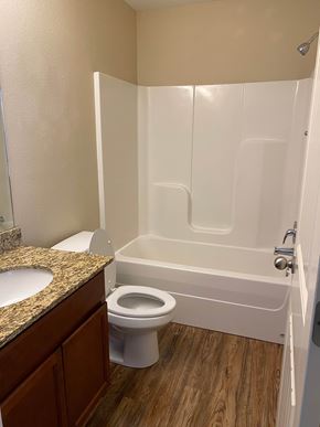Centerton house for rent - A white toilet sits next to a bathtub in a bathroom.
