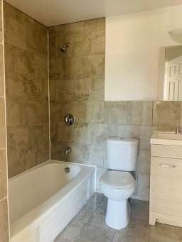 Toronto apartment for rent - A white toilet sits next to a bathtub in a tiled bathroom.
