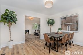 Cincinnati apartment for rent - A room with a wooden table and chairs, a potted plant, and a window with a view of a brick building outside.