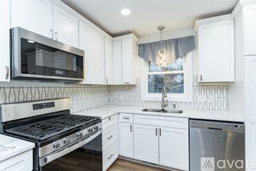 Rochester house for rent - A kitchen with white cabinets and a black stove top oven.