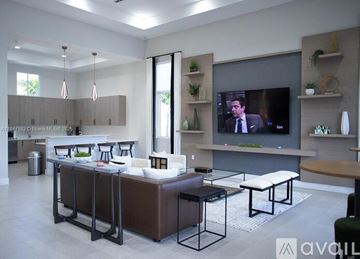 Miami townhouse for rent - A modern living room with a television and a kitchen area in the background.