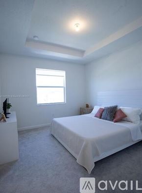 Miami townhouse for rent - A bedroom with a white bed and a window.