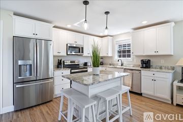 Old Orchard Beach house for rent - A modern kitchen with white cabinets and stainless steel appliances.
