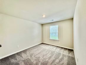 Taylors house for rent - A room with a carpeted floor and a window showing a building outside.