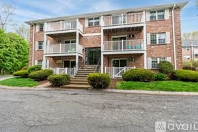 Billerica condo for rent - A brick apartment building with a white balcony and stairs leading to the front door.