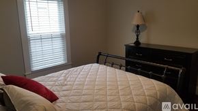 Greenville house for rent - A bedroom with a bed, nightstand, and window with blinds.