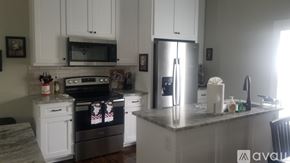 Greenville house for rent - A kitchen with white cabinets and a granite countertop.