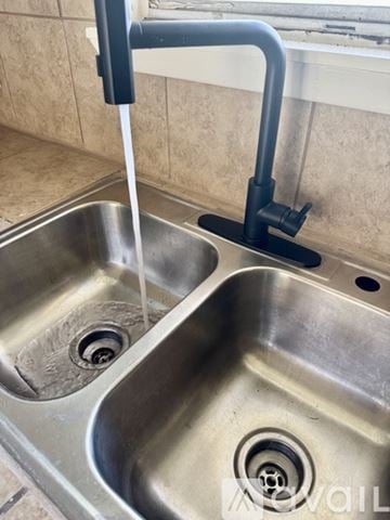 Hutchins house for rent - A kitchen sink with a black faucet and running water.