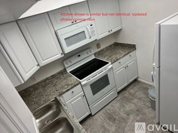 Ocala condo for rent - A kitchen with white cabinets and a granite countertop.