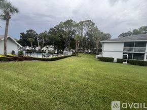 Ocala condo for rent - A grassy area with a house and trees in the background.