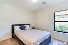 Glendale house for rent - A bedroom with a large bed and a window overlooking a building.