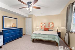 Sandy apartment for rent - A bedroom with a blue dresser and a bed with a white comforter.