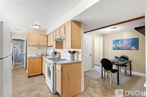 Sandy apartment for rent - A kitchen with wooden cabinets and a dining table with chairs.