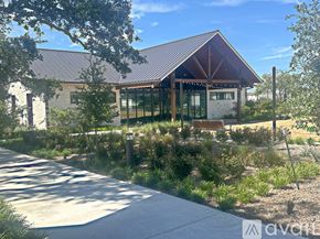 San Antonio house for rent - A modern building with a red roof and glass windows is surrounded by greenery.