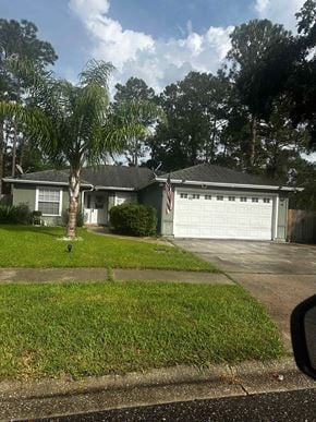 Jacksonville house for rent - A house with a garage and a tree in front.