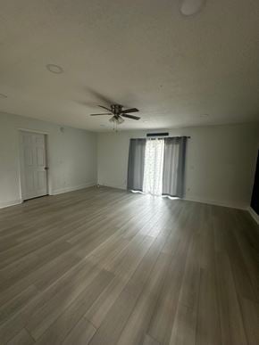 Jacksonville house for rent - A room with a ceiling fan and light, wooden floors, and a window with curtains.