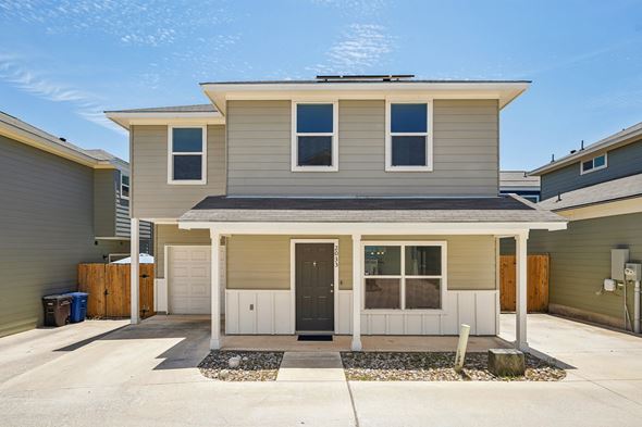 San Antonio house for rent - A house with a grey roof and white walls with a black mat in front.