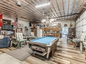 Harrah house for rent - A pool table is in the middle of a room with a wooden floor and a ceiling with exposed pipes.