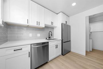 San Diego apartment for rent - A kitchen with white cabinets and a grey refrigerator.