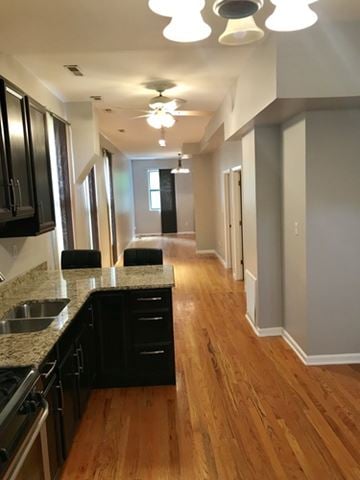 Chicago house for rent - A kitchen with black cabinets and a wooden floor.