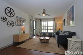 Tampa apartment for rent - A living room with a black couch, a wooden coffee table, and a ceiling fan.