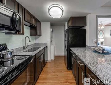 Tampa apartment for rent - A kitchen with black appliances and wooden floors.