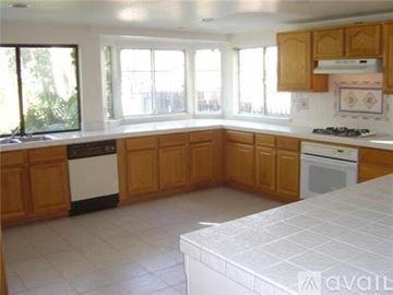 Mission Viejo house for rent - A kitchen with wooden cabinets and white appliances.