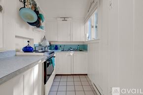 York house for rent - A kitchen with white cabinets and a blue vase on the counter.