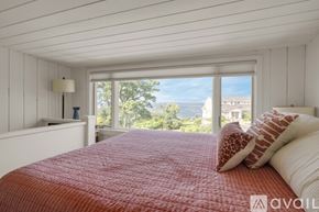 York house for rent - A bedroom with a red bedspread and a window overlooking the ocean.