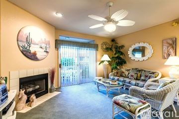 Phoenix condo for rent - A living room with a fireplace, a couch, a chair, a coffee table, a potted plant, a mirror, and a painting on the wall.