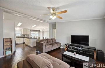 Denver house for rent - A living room with a brown couch and a television on a black stand.