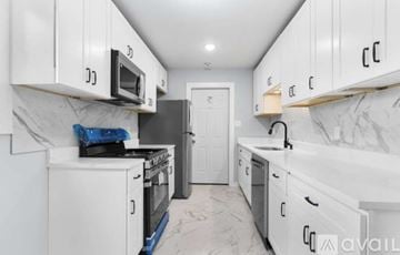 Gary house for rent - A kitchen with white cabinets and a marble floor.