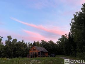 Campton house for rent - A house is situated in a field with trees around it.