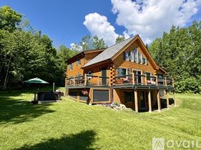 Campton house for rent - A wooden house with a deck and a hot tub in the yard.