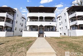 Baltimore apartment for rent - A white building with a brown roof and a walkway leading to the entrance.