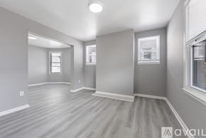Baltimore apartment for rent - A spacious room with wooden flooring and white walls.