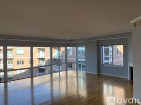 Alexandria condo for rent - A spacious room with wooden floors and large windows overlooking a cityscape.