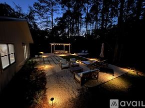 Santa Rosa Beach house for rent - A backyard with a patio and a gazebo is lit up at night.