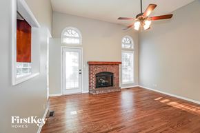 Clarksville house for rent - A spacious room with a fireplace and a ceiling fan.
