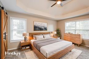 Clarksville house for rent - A bedroom with a large bed, a ceiling fan, and a painting on the wall.