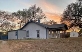Littlefield house for rent - A small house with a porch and a chimney is surrounded by trees.