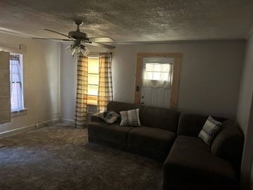 Littlefield house for rent - A living room with a brown couch and a ceiling fan.