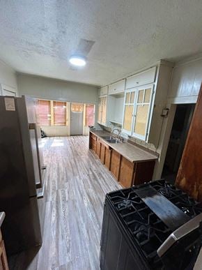 Littlefield house for rent - A kitchen with a black stove top oven and wooden flooring.